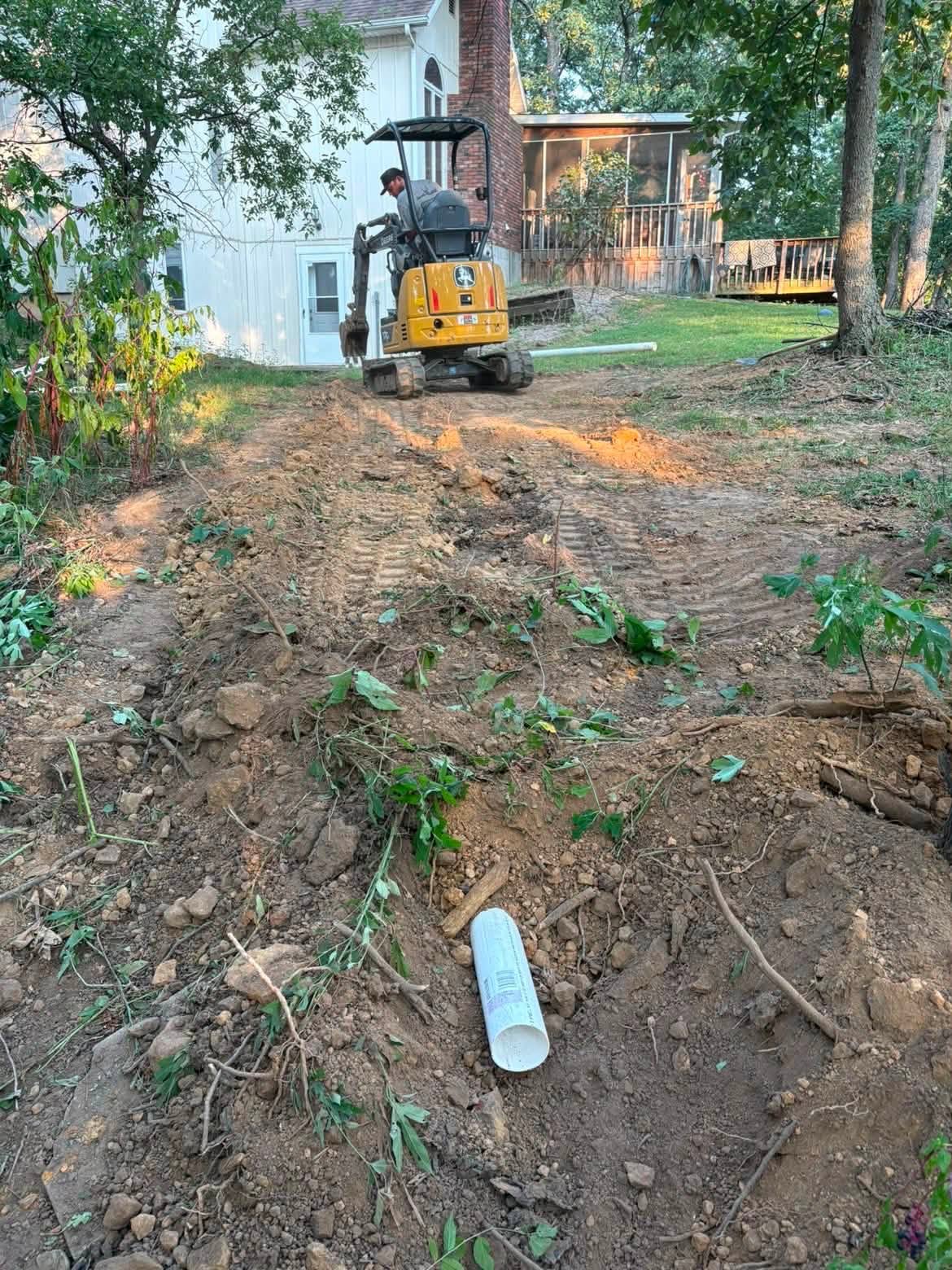 Mini excavator laying PVC pipe during sewer work in Vernon County, MO Mini excavator laying PVC pipe during sewer work in Vernon County, MO