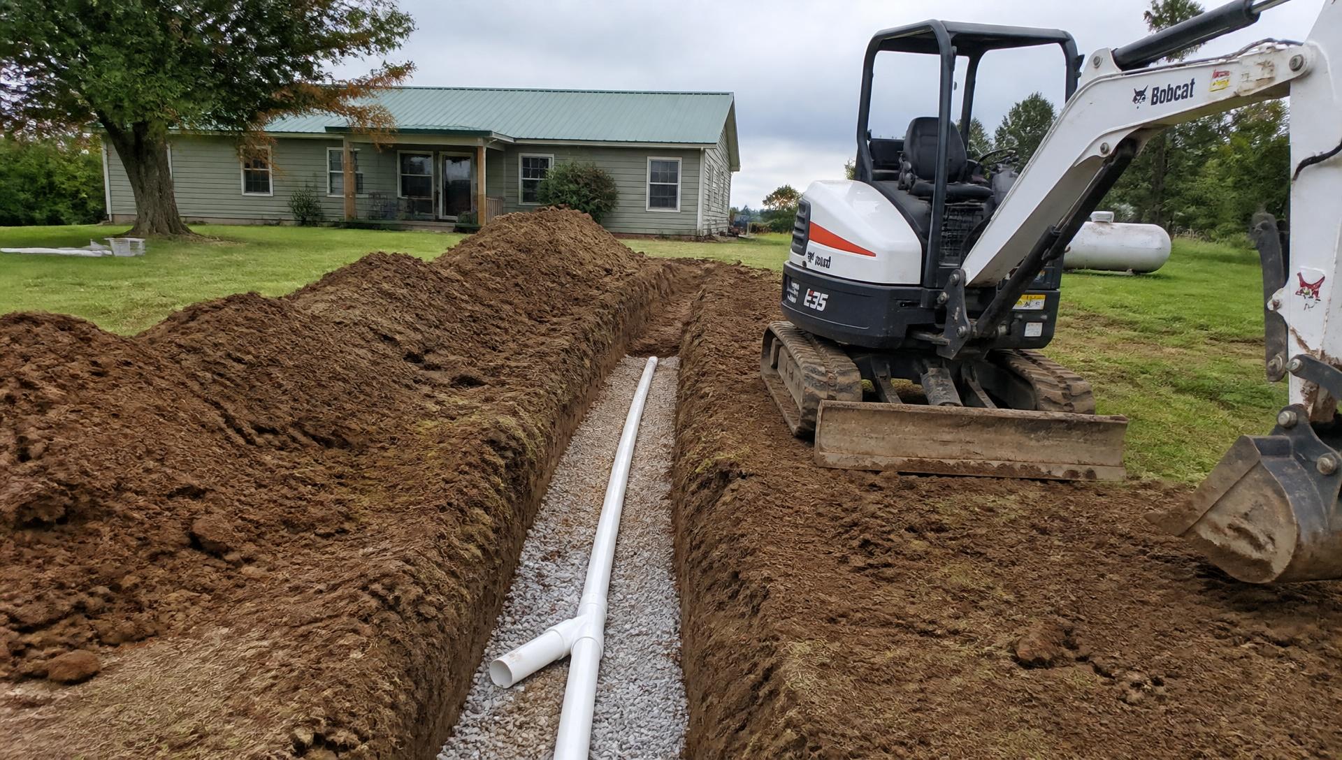 Sewer and plumbing excavation serving Richards, MO and Vernon County Plumbing contractor operating a mini excavator for sewer excavation in Richards, MO